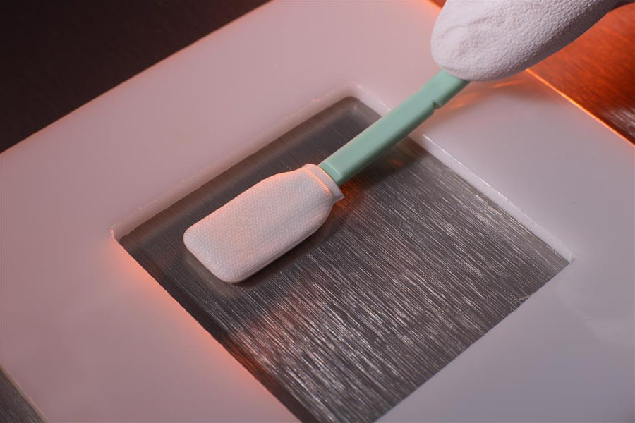 Swab sampling performed using a template on stainless steel surface in a controlled environment.